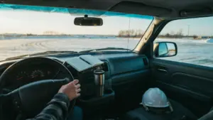 Parked pickup truck at dusk in a snowy Saskatchewan lot, with a short handwritten list on the dashboard — a quiet pause between work and home